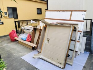 回収前の様子。ユニットバスのパネルや洗面台、木材、袋詰めの廃材が、養生材の上に仮置きされていました。