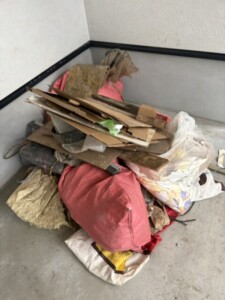 小金井市の住宅新築現場のガレージに、手直し工事で出た段ボールや板材、袋詰めの廃材が積まれている様子