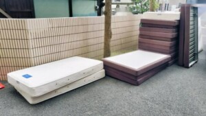 町田市のホテル改装で出たマットレスとベッドの土台が屋外に置かれている様子